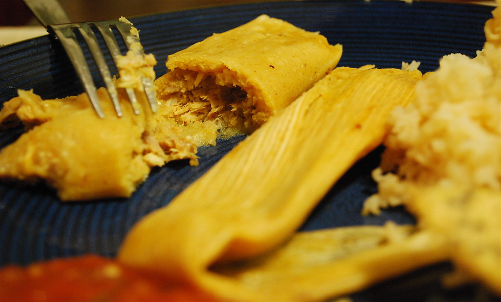 A tamale opened up to show the masa and filling