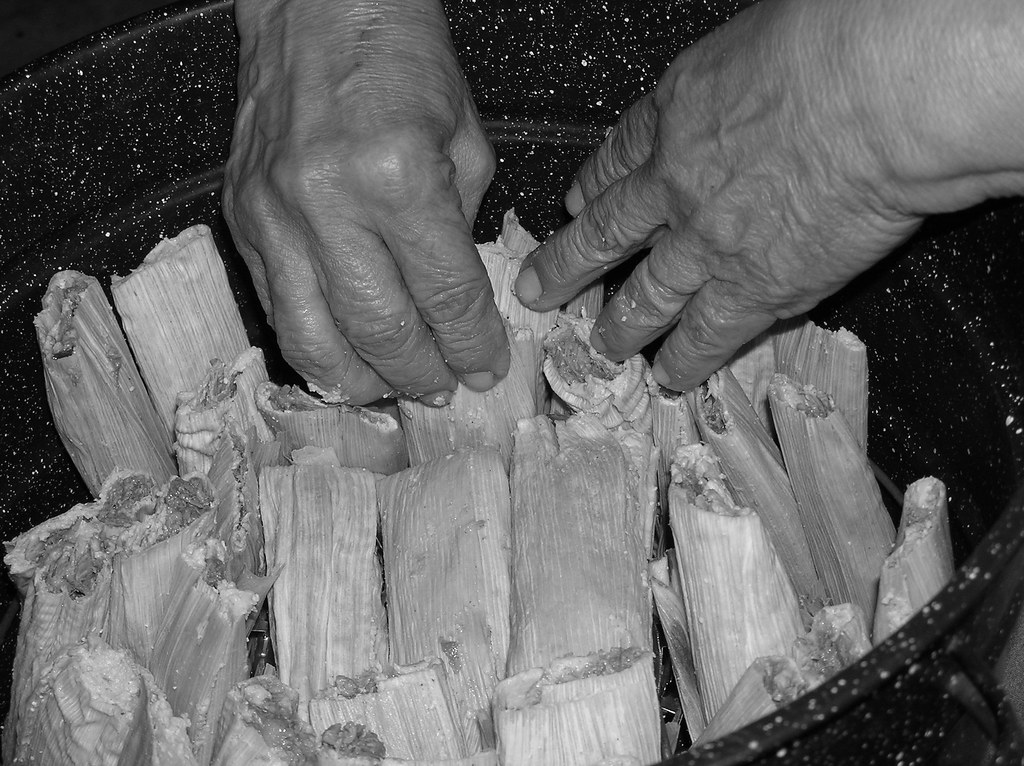 Hands arranging tamales in a pot, the last step before steaming